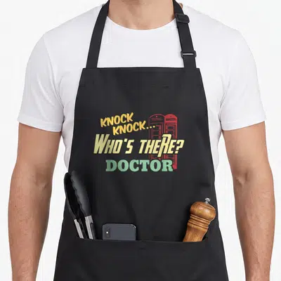 Tablier de cuisine noir avec texte Knock Knock Who's There Doctor et deux téléphones rouges en arrière-plan.