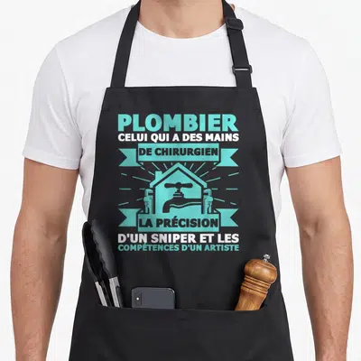 Tablier de cuisine noir avec inscription Plombier celui qui a des mains de chirurgien et illustration de robinet turquoise.