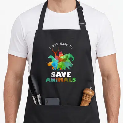 Tablier de cuisine noir avec des silhouettes animales colorées et le texte « I WAS MADE TO SAVE ANIMALS » imprimé en blanc et multicolore.