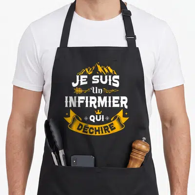 Tablier de cuisine noir avec l'inscription Je Suis Un Infirmier Qui Déchire en blanc et jaune sur fond uni.