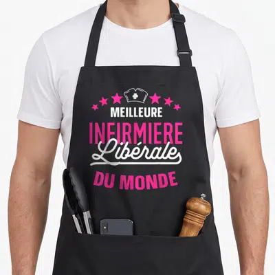 Tablier de cuisine noir avec inscription Meilleure infirmière libérale du monde en rose et blanc sous un calot stylisé.