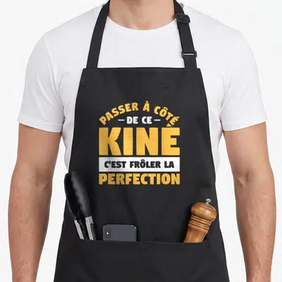 Tablier de cuisine noir avec l'inscription jaune et blanche Passer à côté de ce Kine c'est frôler la perfection.