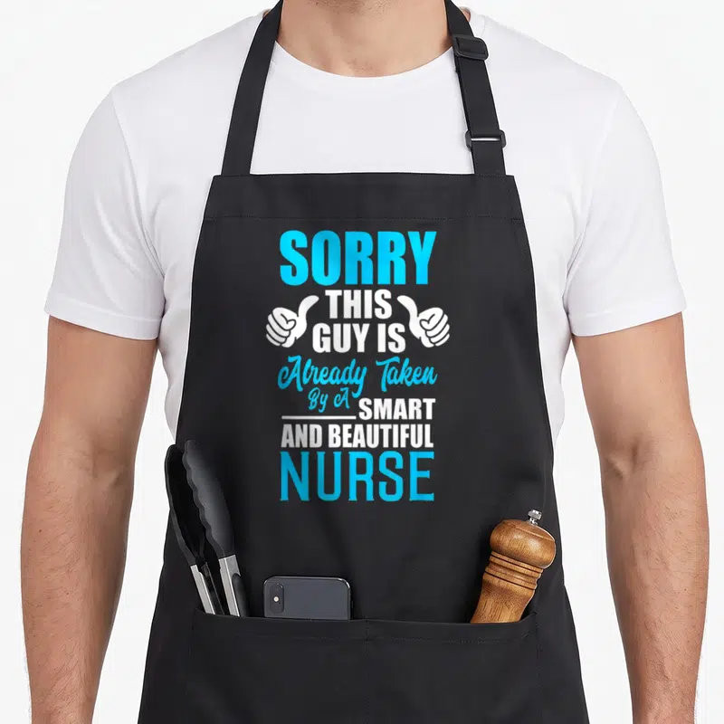 Tablier de cuisine noir avec le texte « Sorry This Guy is Already Taken By A Smart And Belle Nurse » en bleu et blanc.