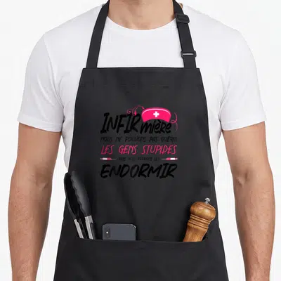 Tablier de cuisine noir avec inscription infirmière humoristique, coiffe rose à croix blanche et motifs de seringues roses.