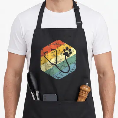 Tablier de cuisine noir avec motif hexagonal arc-en-ciel, stéthoscope gris et empreinte de patte animalière stylisée.