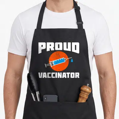 Tablier de cuisine noir avec seringue bleue sur cercle orange et texte blanc Proud Vaccinator