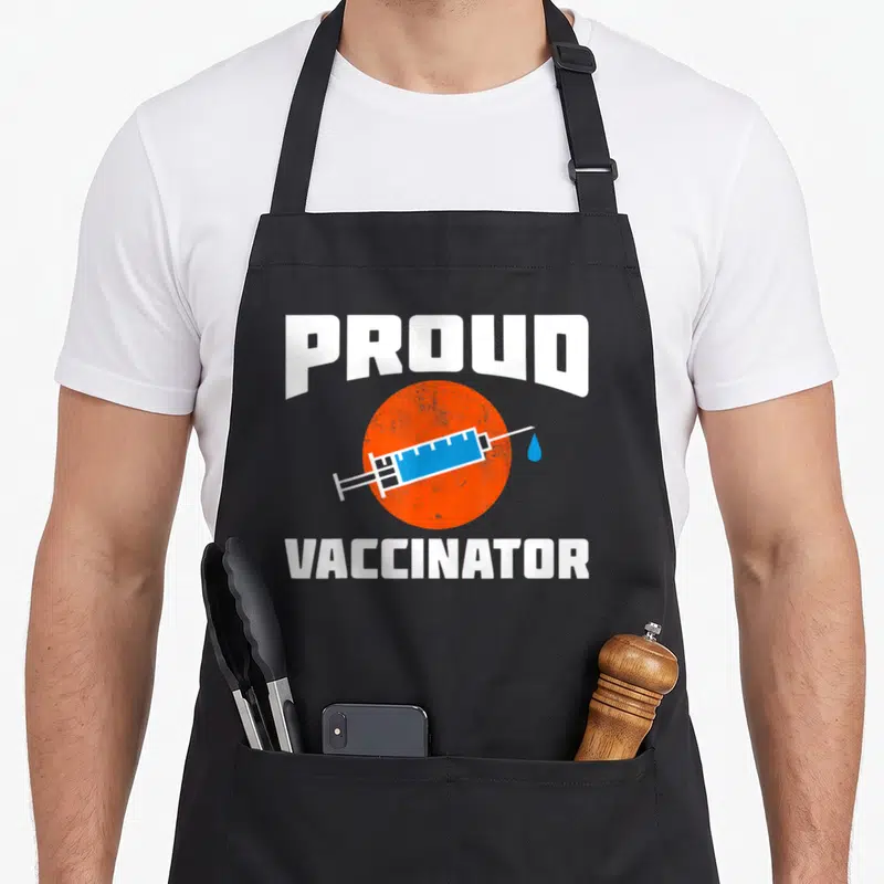 Tablier de cuisine noir avec seringue bleue sur cercle orange et texte blanc Proud Vaccinator
