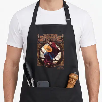 Tablier de cuisine noir avec illustration du Docteur Strange et son sceau magique doré dans un cadre ornemental.