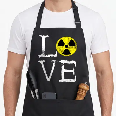 Tablier de cuisine noir avec le mot Love où l'o est un symbole radiation jaune et noir, texte blanc usé.