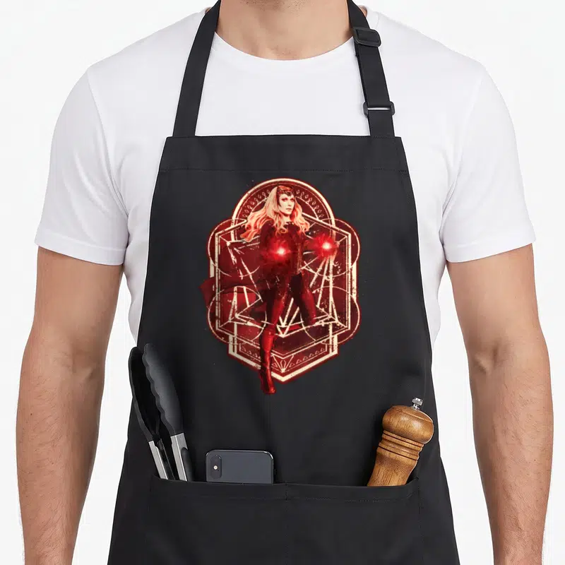 Tablier de cuisine noir avec illustration rouge et blanche de la Sorcière Rouge entourée de symboles magiques géométriques.