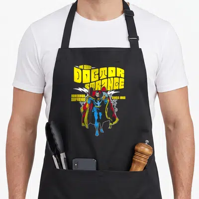 Tablier de cuisine noir avec illustration rétro du Docteur Strange et texte jaune The Genius Doctor Strange Since 1963.