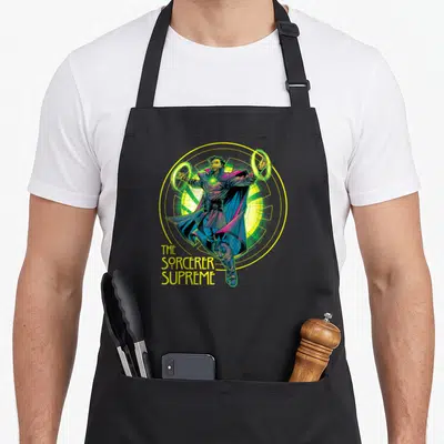 Tablier de cuisine noir avec illustration du Sorcier Suprême et anneaux magiques jaunes et verts.