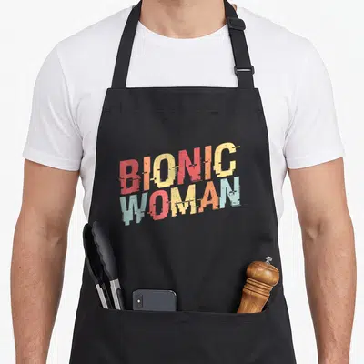 Tablier de cuisine noir avec inscription Bionic Woman en lettres colorées et effet dégradé vintage.