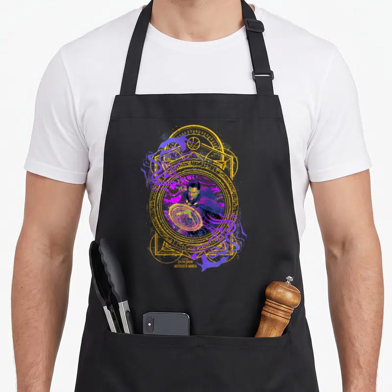 Tablier de cuisine noir avec illustration colorée du Docteur Strange et un portail magique circulaire doré et violet.