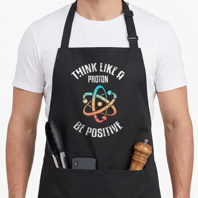 Tablier de cuisine noir avec inscription Pensez comme un proton soyez positif et symbole atomique coloré vintage.