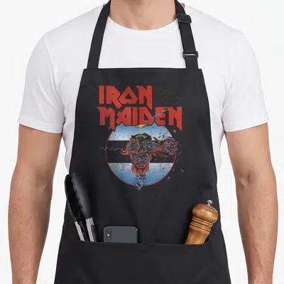 Tablier de cuisine noir avec illustration d'Eddie squelettique et texte Iron Maiden en rouge.