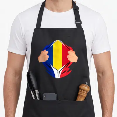 Tablier de cuisine noir avec illustration de mains écartant une chemise revealing le drapeau tricolore roumain bleu jaune rouge.