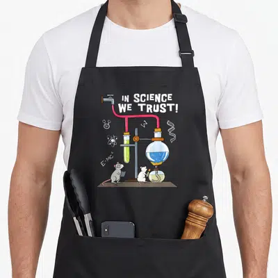 Tablier de cuisine noir avec illustration de souris en labo, texte In Science We Trust et équipements scientifiques colorés.