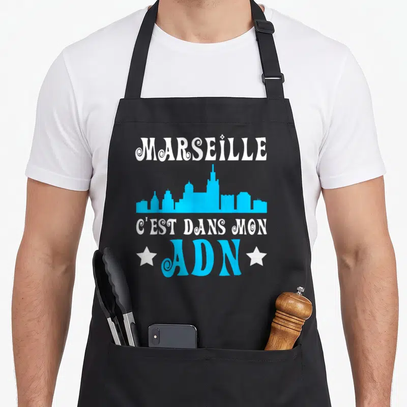 Tablier de cuisine noir avec skyline bleu et texte blanc Marseille c'est dans mon ADN ADN encadré d'étoiles blanches