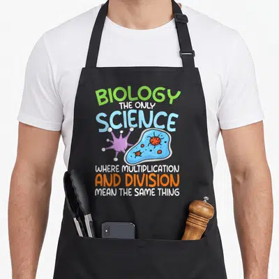 Tablier de cuisine noir avec une citation humoristique sur la biologie en lettres vertes, bleues et orange accompagnée d'illustrations de microbes.