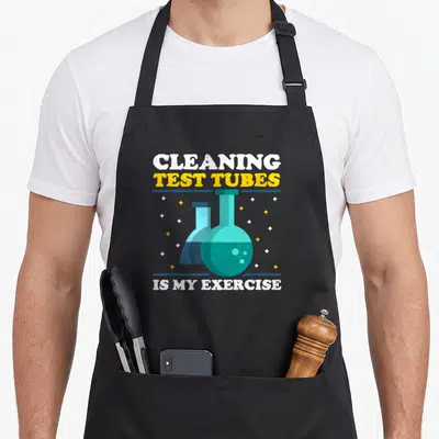 Tablier de cuisine noir avec deux fioles chimiques bleues et le texte Cleaning Test Tubes Is My Exercise en jaune et blanc.