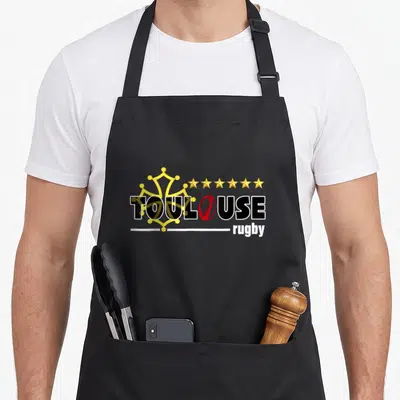 Tablier de cuisine noir avec logo Toulouse Rugby, cinq étoiles dorées et symbole occitan stylisé en jaune sur fond uni.