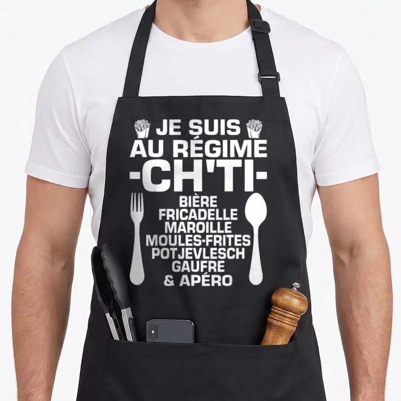 Tablier de cuisine noir avec inscription blanche Je suis au régime ch'ti entouré d'une fourchette, d'une cuillère et de frites.