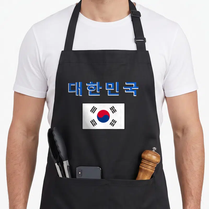 Tablier de cuisine noir avec le drapeau de la Corée du Sud et des caractères bleus en haut.