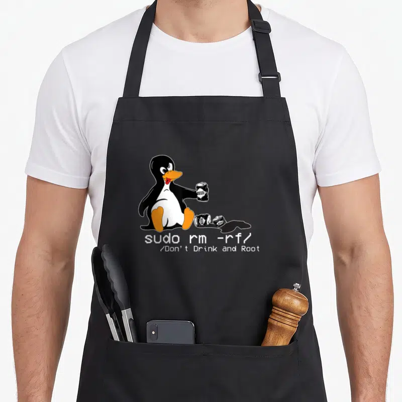 Tablier de cuisine noir avec illustration d'un pingouin Tux Linux assis tenant une canette de bière et des textes en pixel art.