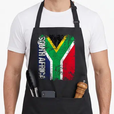 Tablier de cuisine noir avec le drapeau de l'Afrique du Sud et l'inscription SOUTH AFRICA en blanc vertical sur le côté gauche.