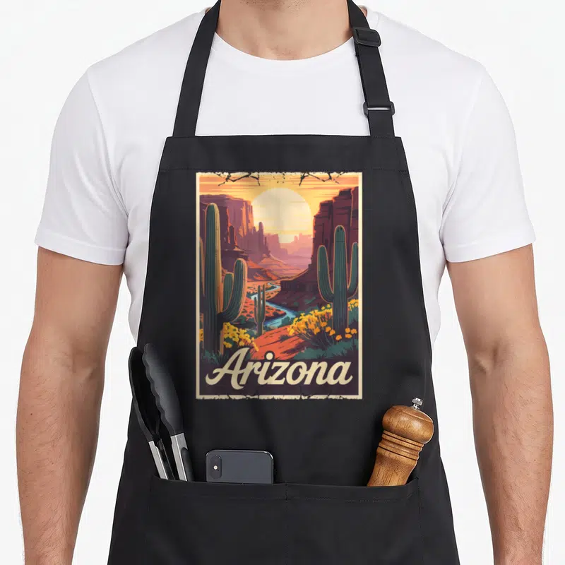 Tablier de cuisine noir avec illustration d'un désert arizonien, cactus et texte Arizona en bas.