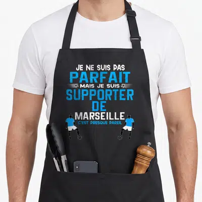 Tablier de cuisine noir avec texte bleu et blanc et deux silhouettes de footballeurs en tenue marseillaise.