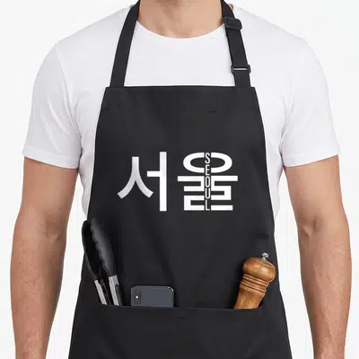 Tablier de cuisine noir avec inscription Seoul en lettres latines verticales intégrées aux caractères d'écriture Hangul blancs.