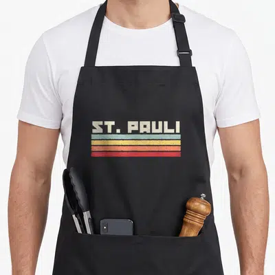 Tablier de cuisine noir avec inscription ST. PAULI et quatre bandes horizontales colorées style rétro.