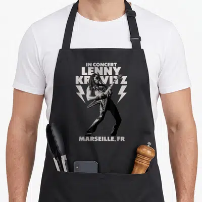 Tablier de cuisine noir avec illustration monochrome d'un musicien jouant de la guitare et le texte In Concert Lenny Kravitz Marseille FR.