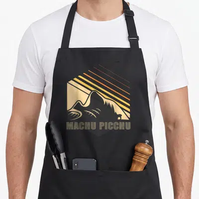 Tablier de cuisine noir avec illustration rétro de Machu Picchu et rayons de soleil orange et jaune.