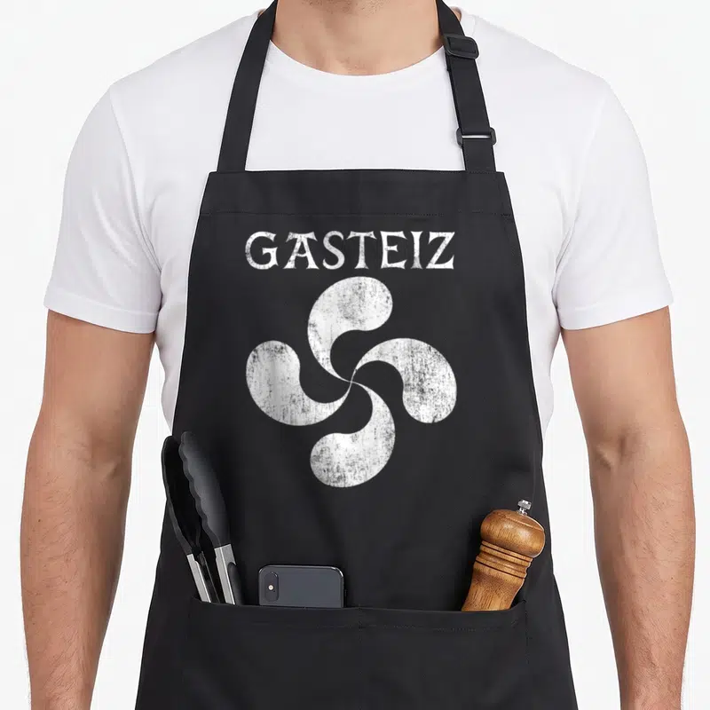 Tablier de cuisine noir avec inscription Gasteiz et symbole lauburu blanc stylisé au centre.