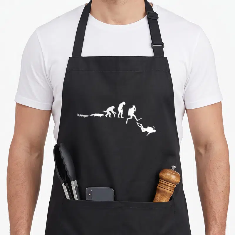 Tablier de cuisine noir avec une illustration blanche représentant l'évolution d'un poisson vers un plongeur sous-marin équipé de palmes.
