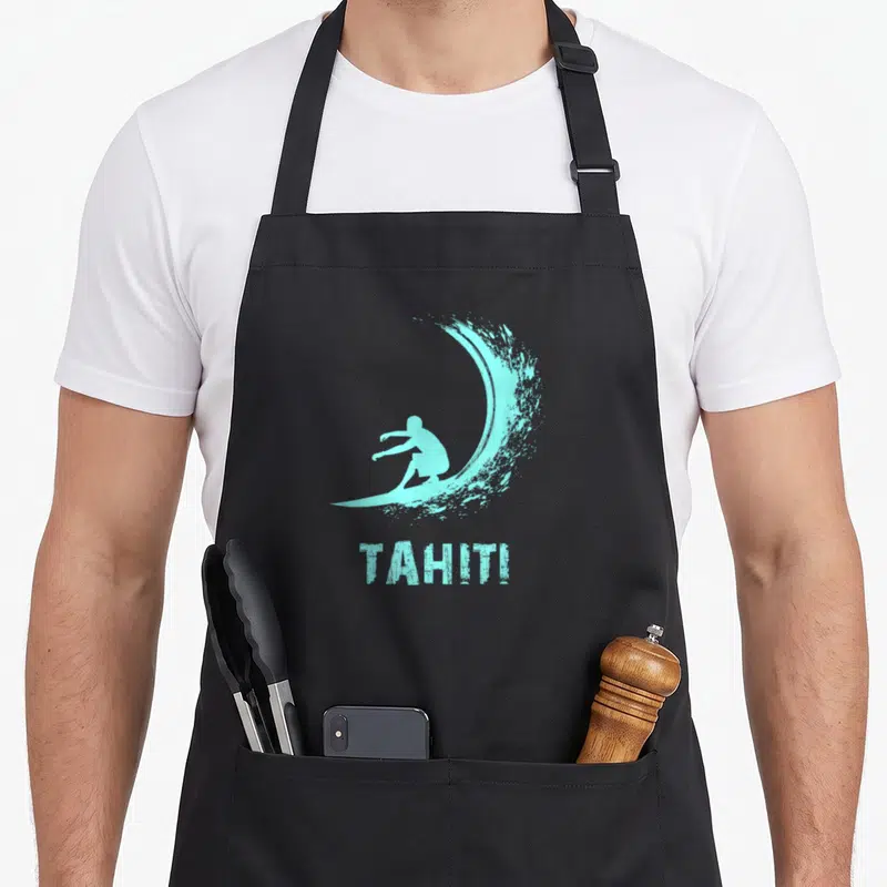 Tablier de cuisine noir avec silhouette de surfeur et vague turquoise ainsi que le mot TAHITI imprimé en bas.