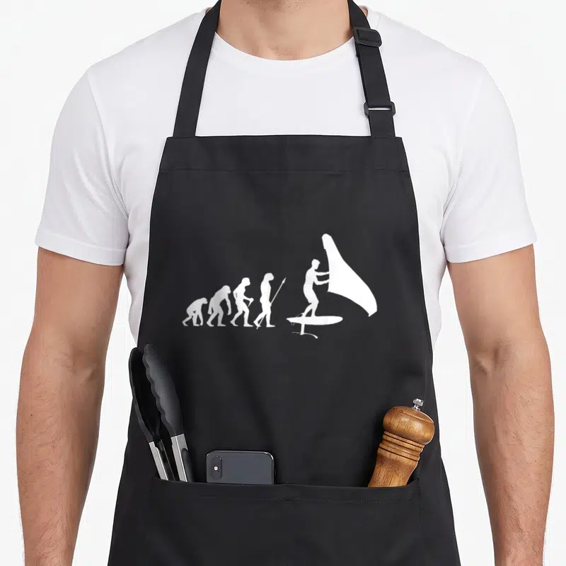 Tablier de cuisine noir avec illustration blanche représentant l'évolution humaine vers le wingfoil et l'hydrofoil.