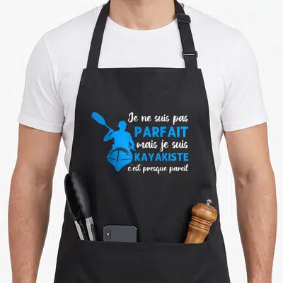 Tablier de cuisine noir avec silhouette bleue de kayakiste et texte Je ne suis pas parfait mais je suis kayakiste c'est presque pareil