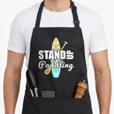 Tablier de cuisine noir avec illustration d'une planche SUP jaune et turquoise et une paddle orange.