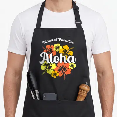 Tablier de cuisine noir avec inscription Aloha et fleurs d'hibiscus orange et jaunes sur fond uni.