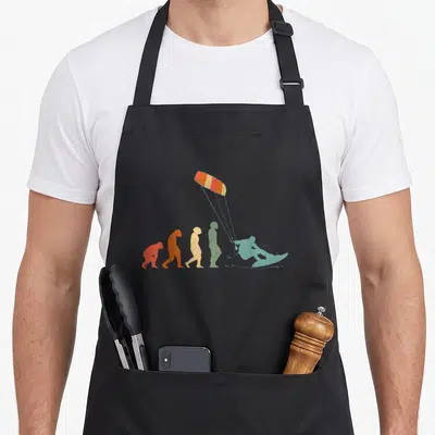Tablier de cuisine noir avec illustration colorée représentant l'évolution du kitesurfeur jusqu'au kitefoil.