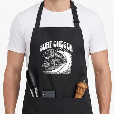 Tablier de cuisine noir avec illustration blanche d'un Sasquatch surfeur et du texte Surf Oregon en style vintage.