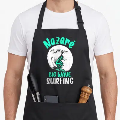 Tablier de cuisine noir avec illustration d'un surfeur sur une grande vague et le texte Nazaré Big Wave Surfing en vert et blanc.