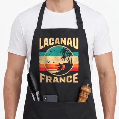 Tablier de cuisine noir avec illustration vintage Lacanau France surfeur et palmiers.