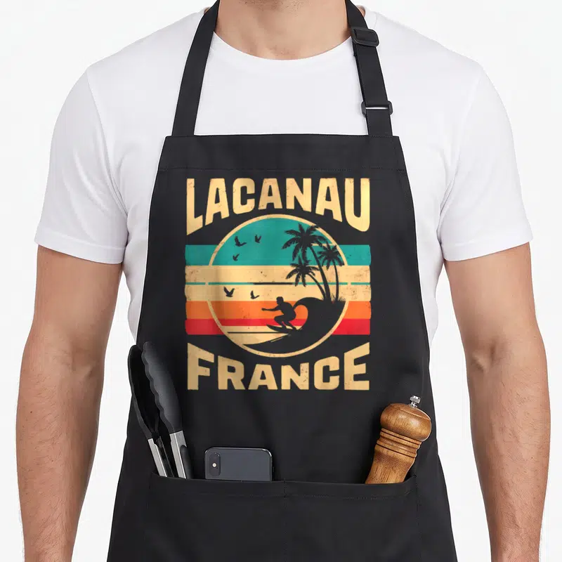 Tablier de cuisine noir avec illustration vintage Lacanau France surfeur et palmiers.