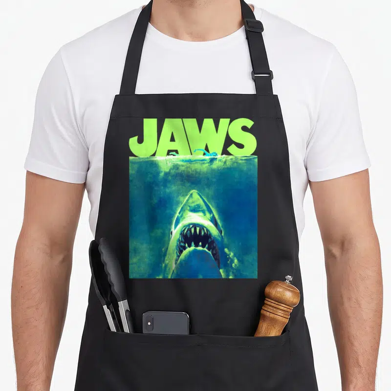 Tablier de cuisine noir avec illustration d'un shark sous l'eau et texte Jaws vert fluo
