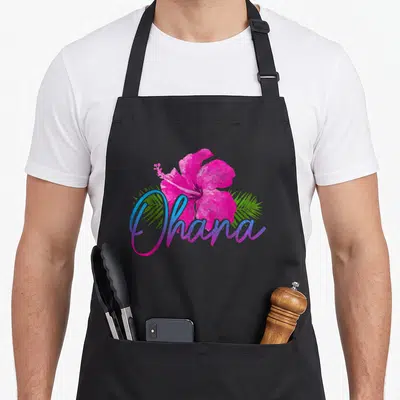 Tablier de cuisine noir avec hibiscus rose et texte Ohana coloré au centre